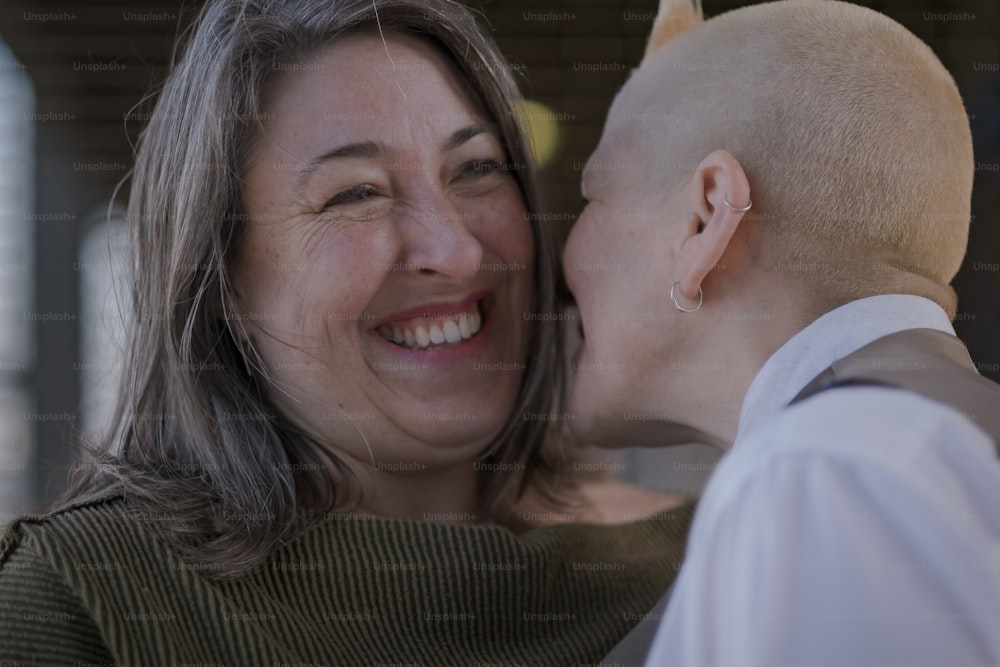 a woman kissing a bald headed man on the cheek