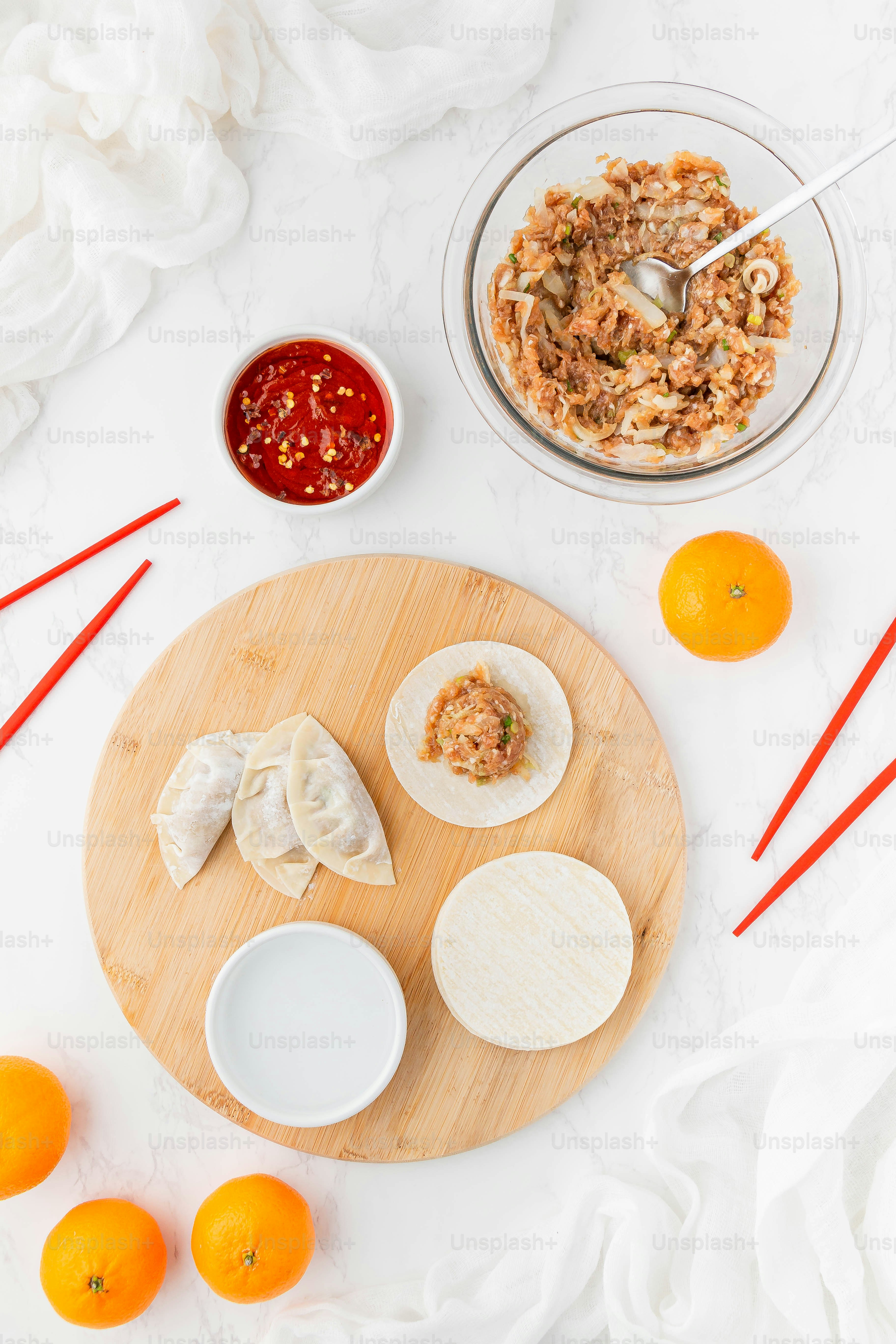 a wooden plate topped with dumplings next to a bowl of sauce