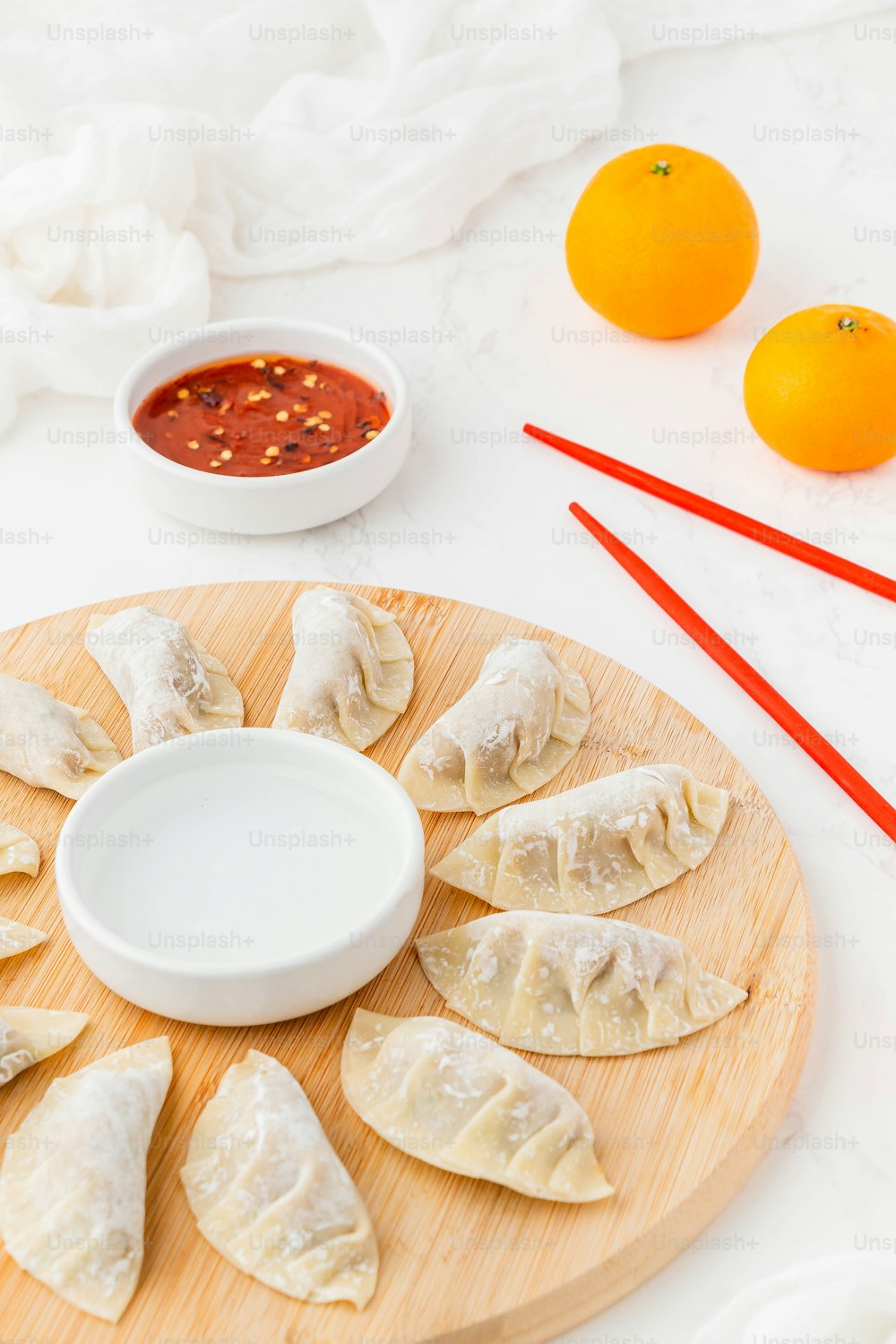 a wooden plate topped with dumplings next to a bowl of sauce