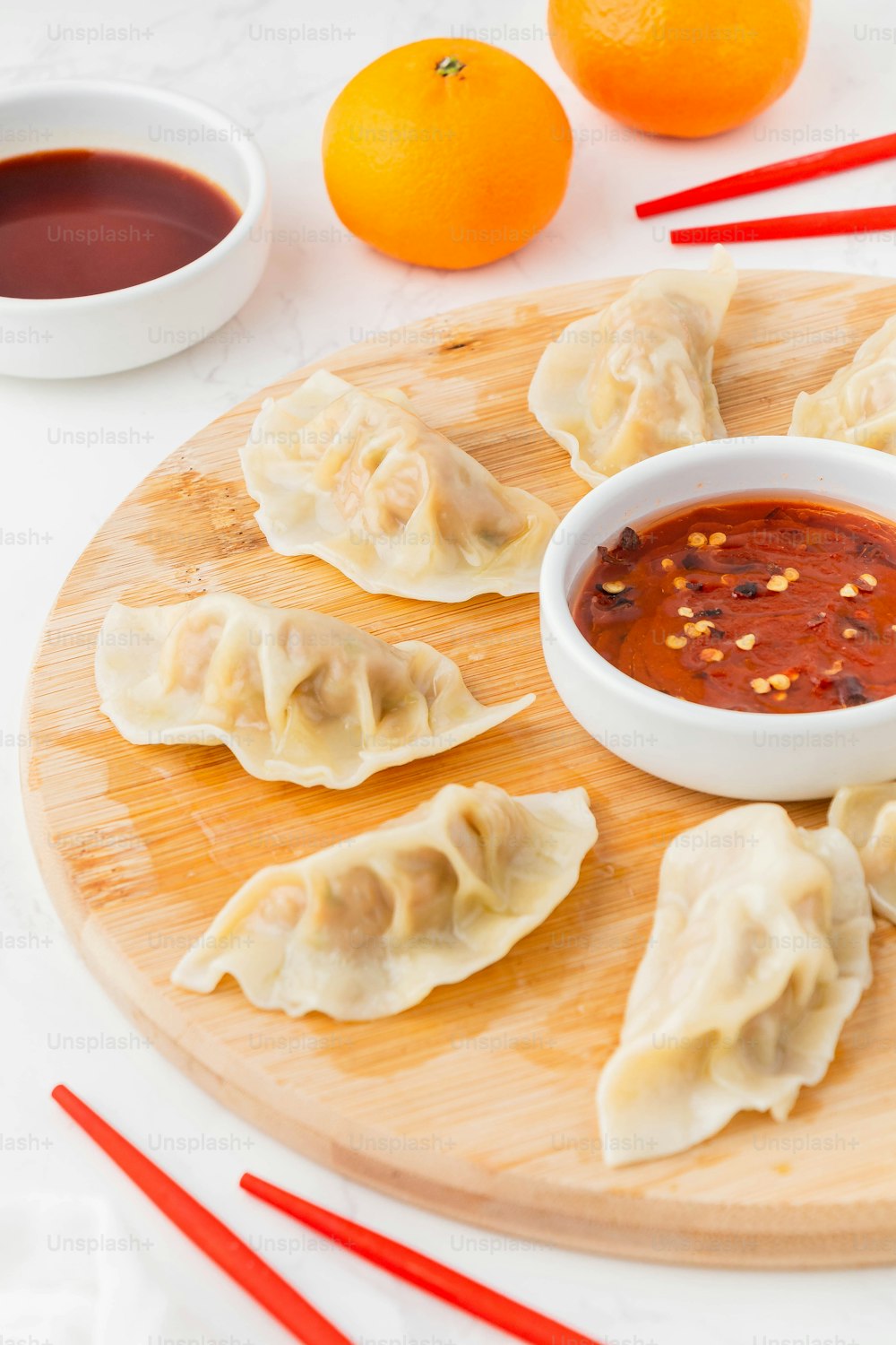 a wooden plate topped with dumplings and sauce