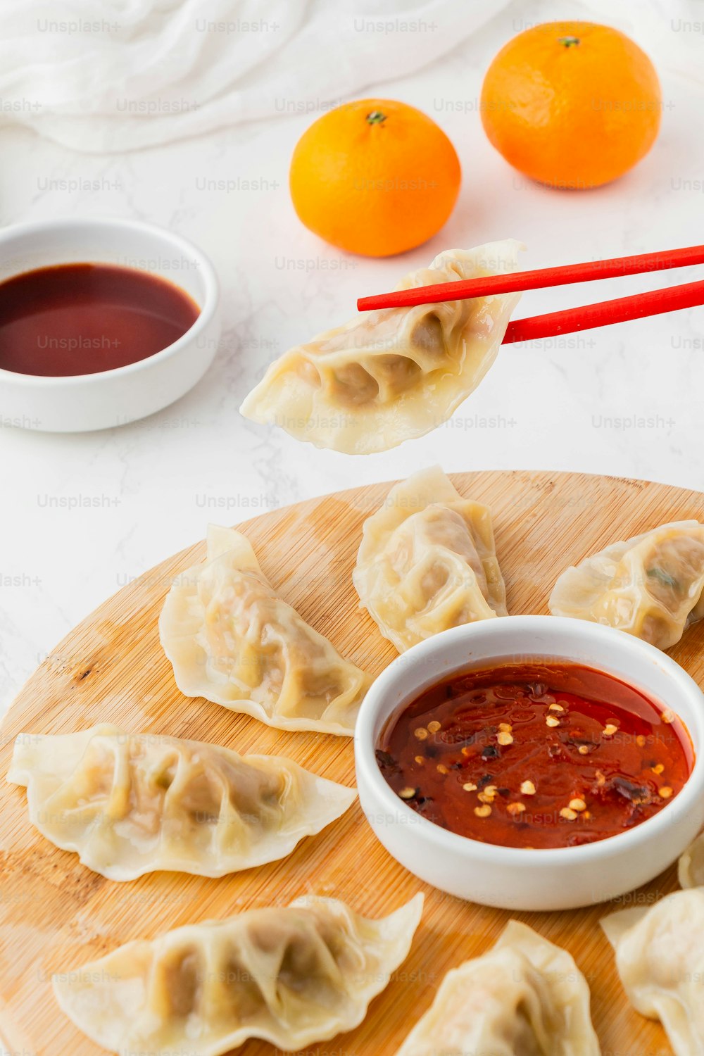 a plate of dumplings with dipping sauce next to oranges