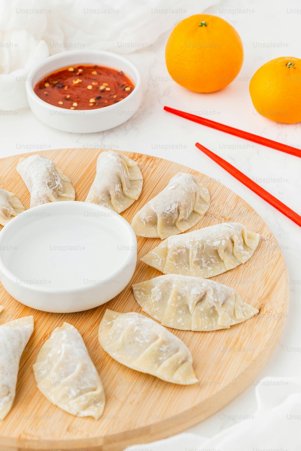 a wooden plate topped with dumplings next to oranges