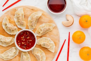 a wooden plate topped with dumplings next to oranges