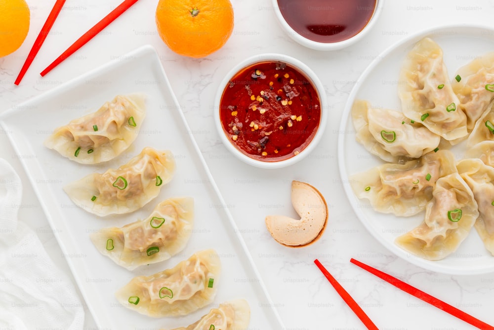 a white plate topped with dumplings next to a bowl of sauce