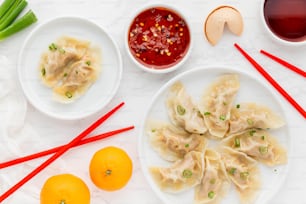 a white plate topped with dumplings next to two oranges