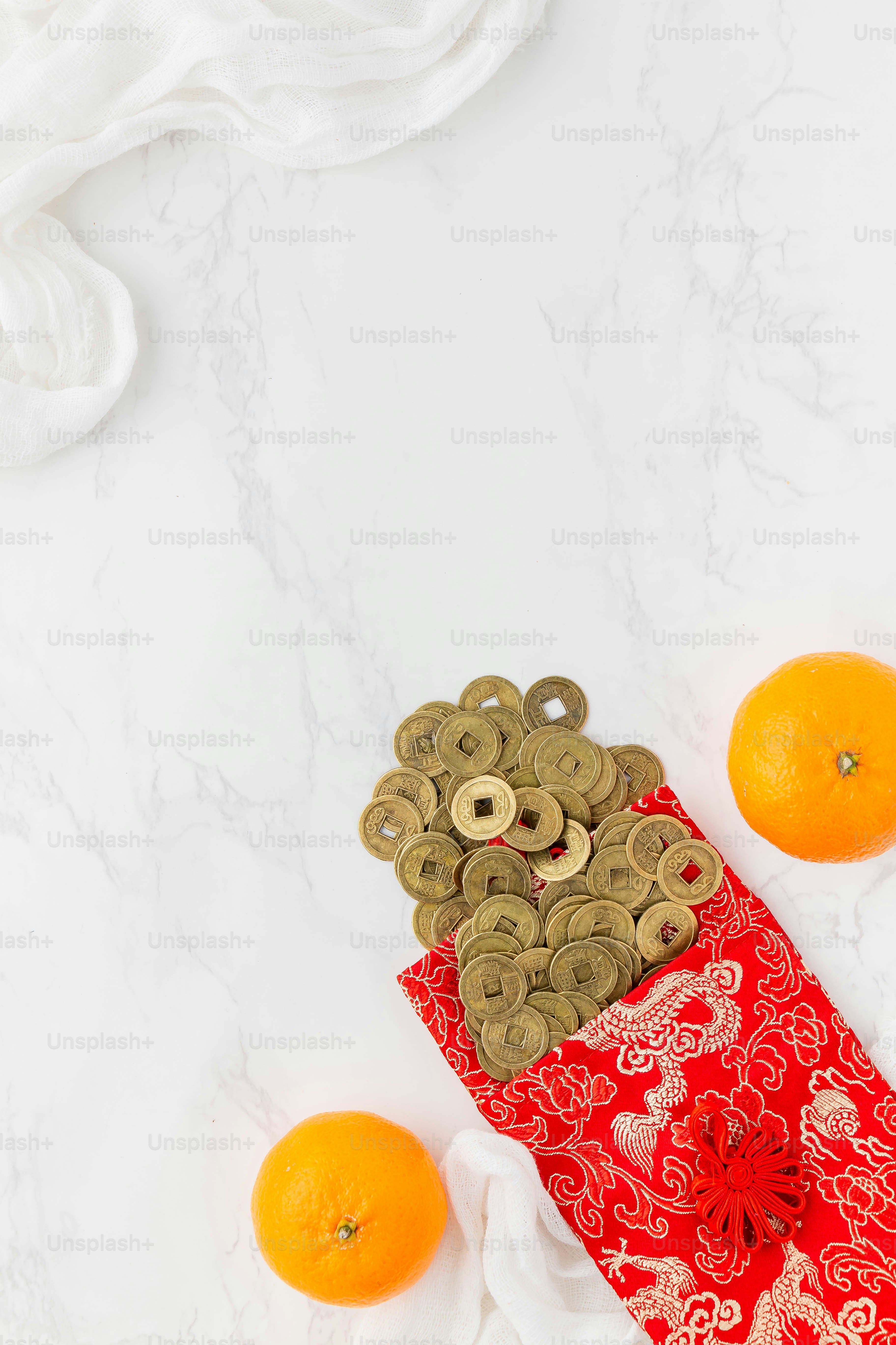Una borsa rossa piena di monete d'oro accanto alle arance