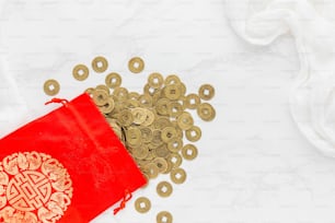 a red bag filled with gold coins on top of a white table