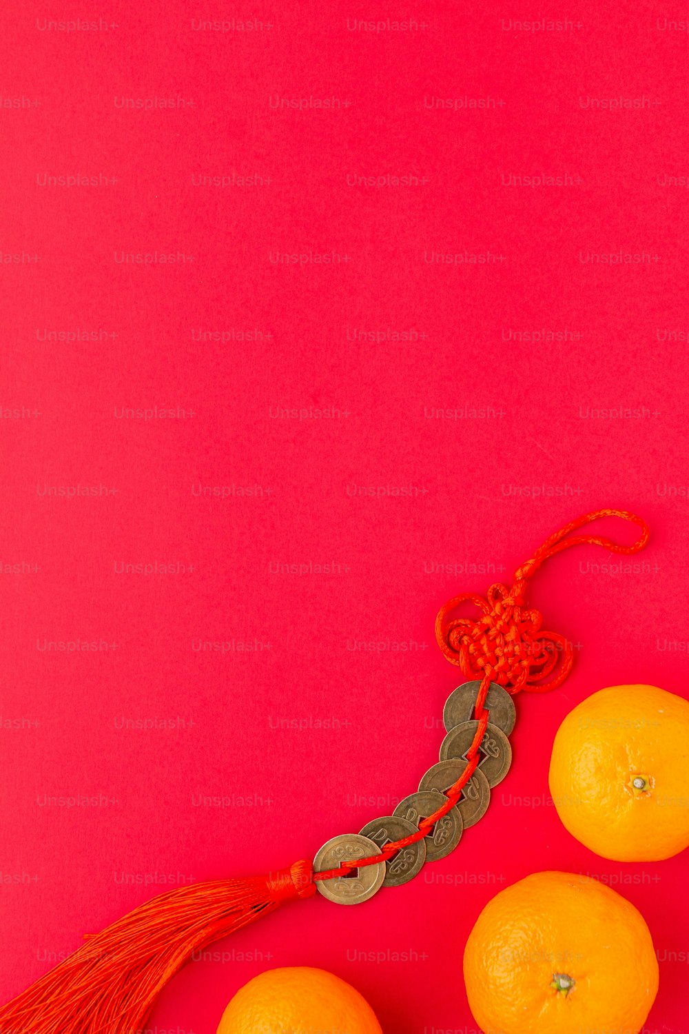 three oranges with a tassel on a pink background