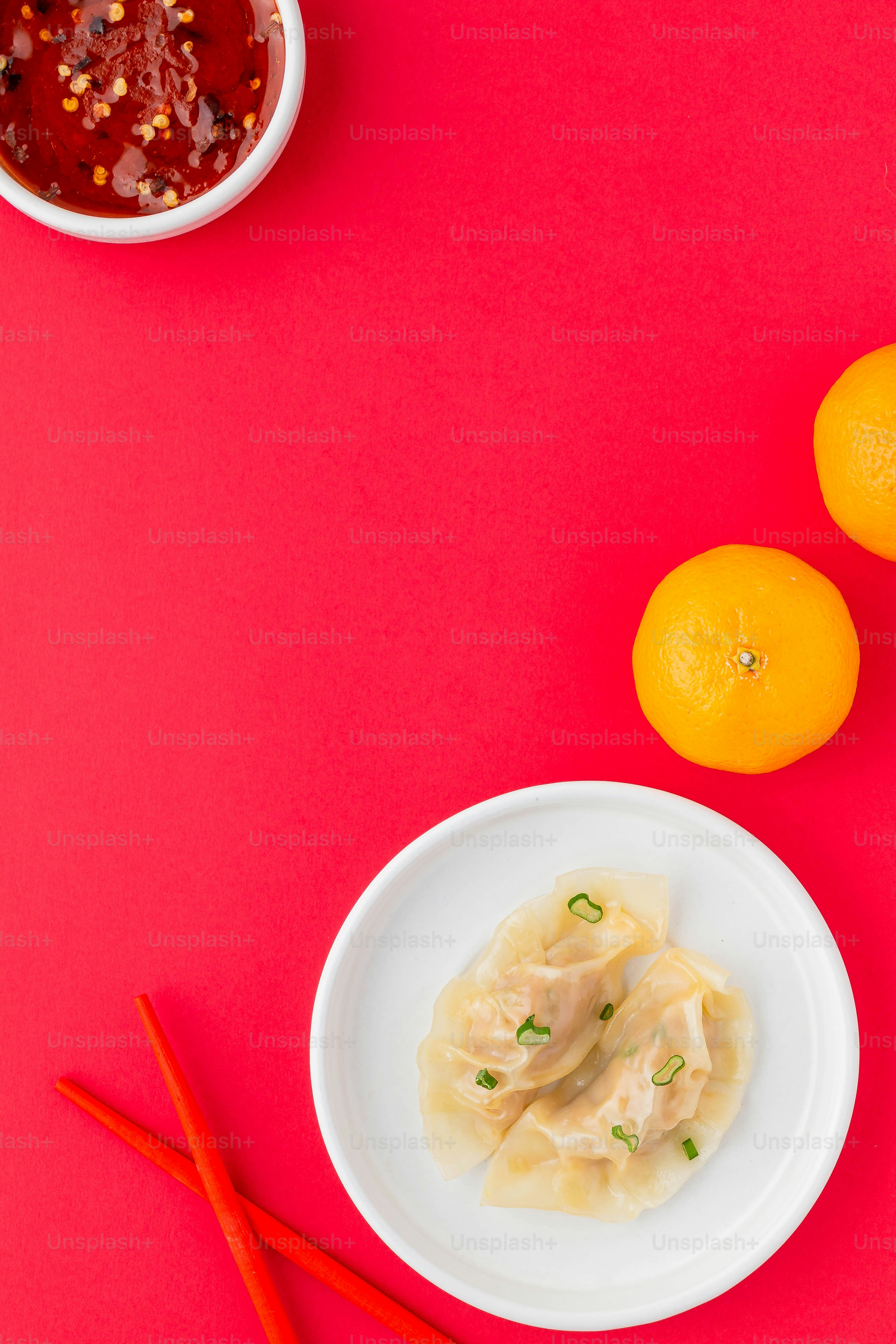 a white plate topped with dumplings next to two oranges