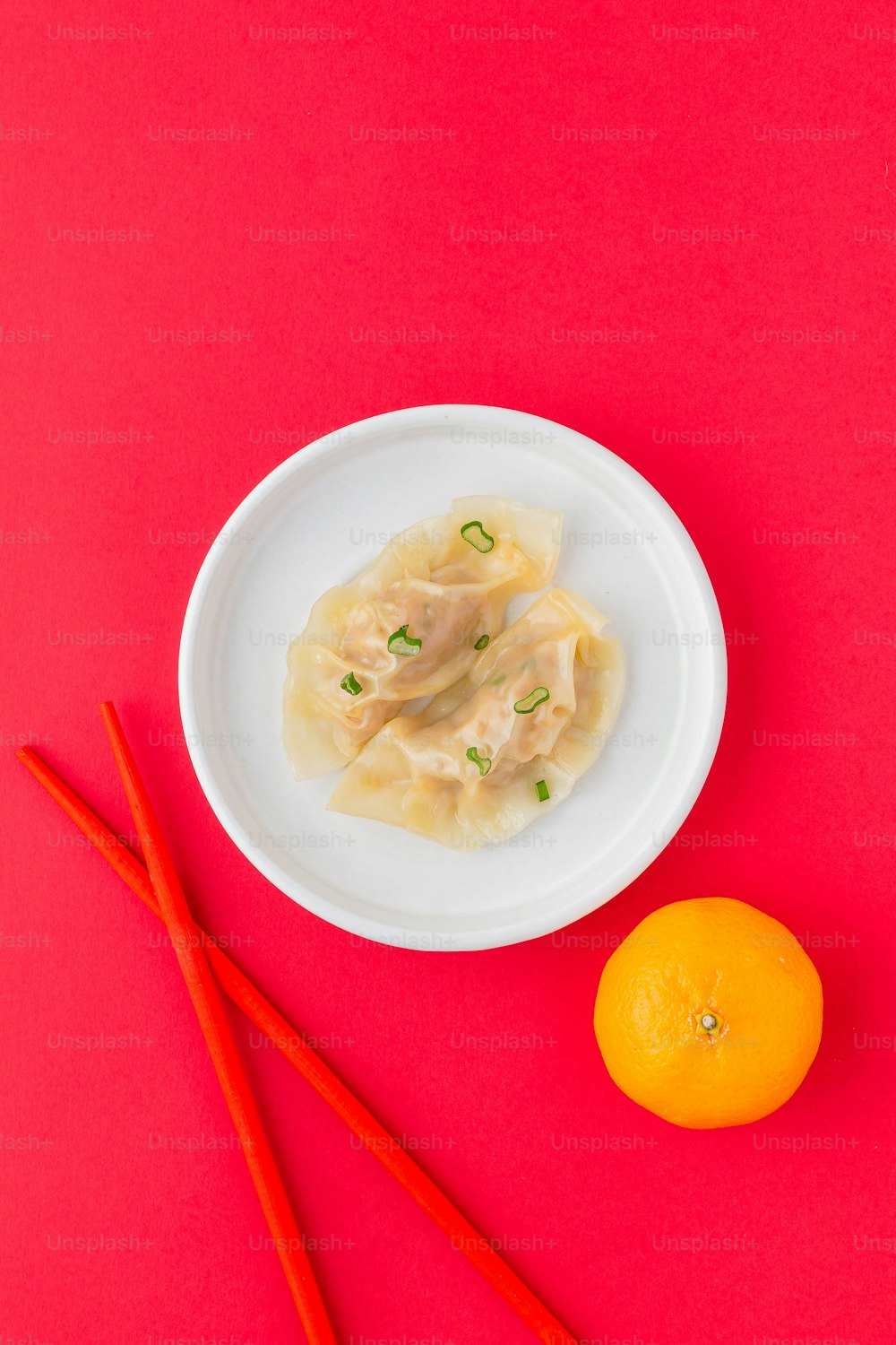 a plate of dumplings next to two chopsticks