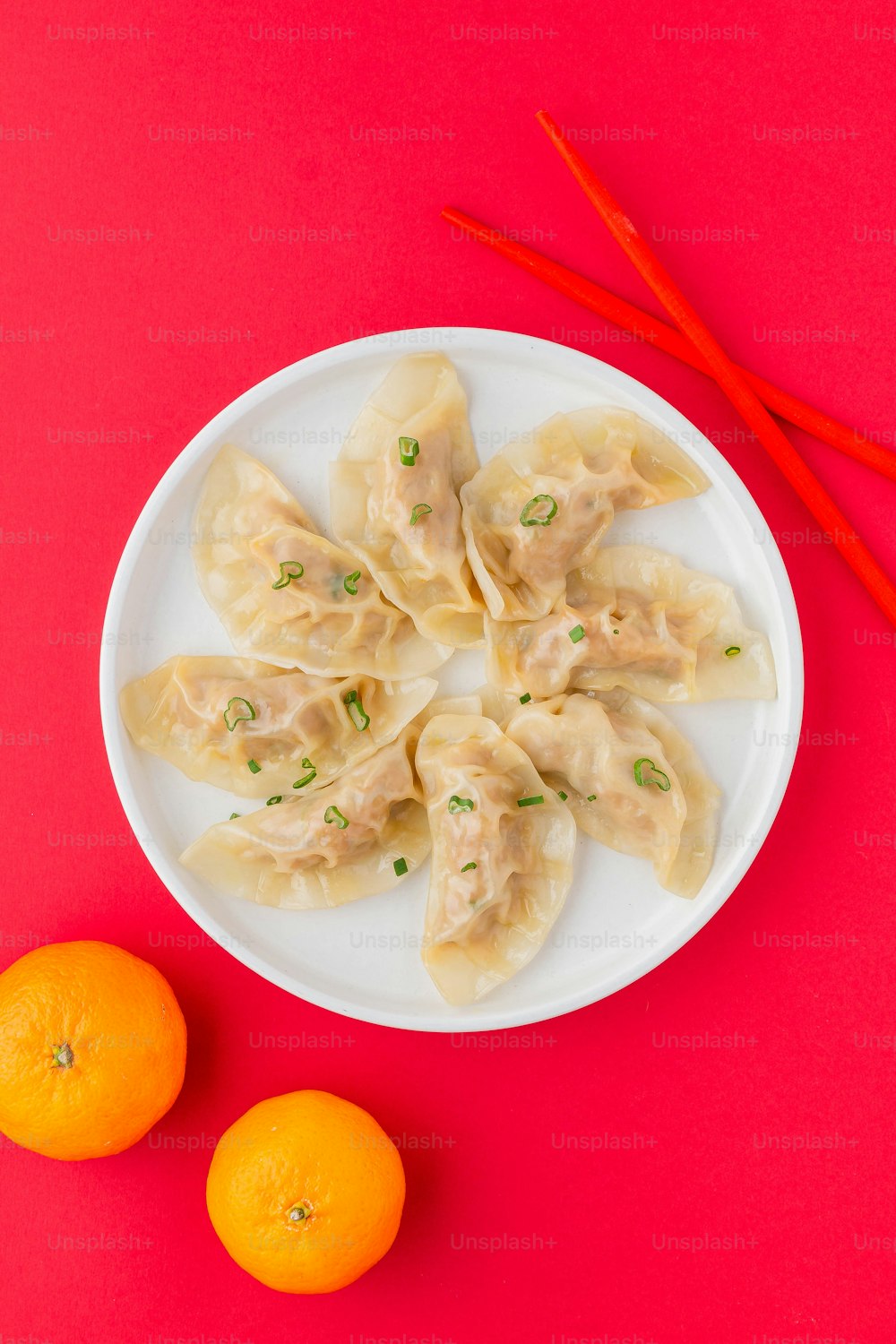 a white plate topped with dumplings next to two oranges