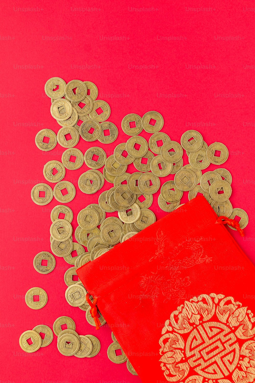 un livre rouge entouré de pièces d’or sur fond rose