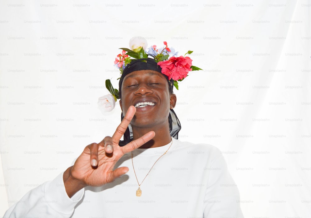 Ein Mann mit einer Blumenkrone auf dem Kopf macht ein Friedenszeichen