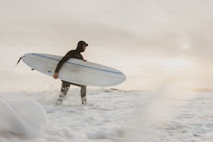 a man in a wet suit carrying a surfboard