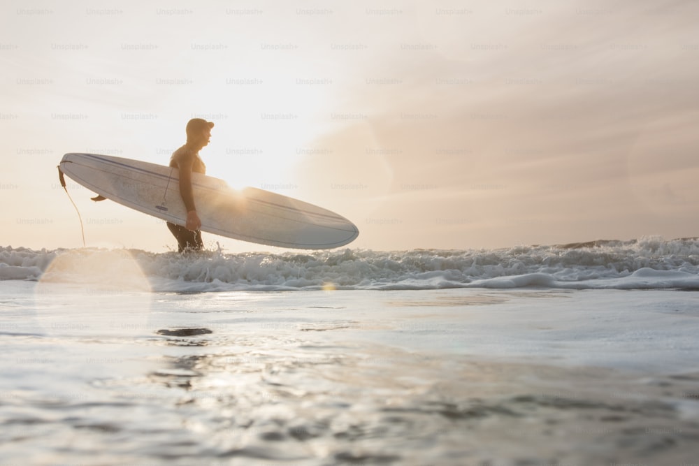 Un uomo che tiene una tavola da surf mentre si trova nell'oceano