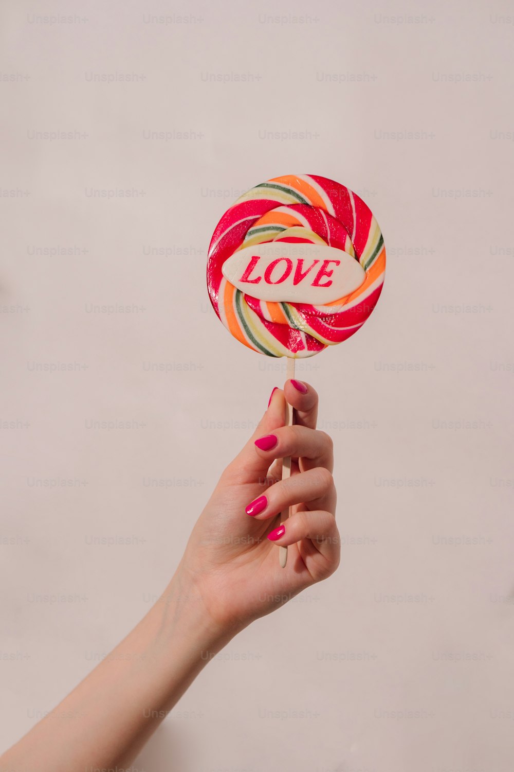 a hand holding a lollipop with the word love on it