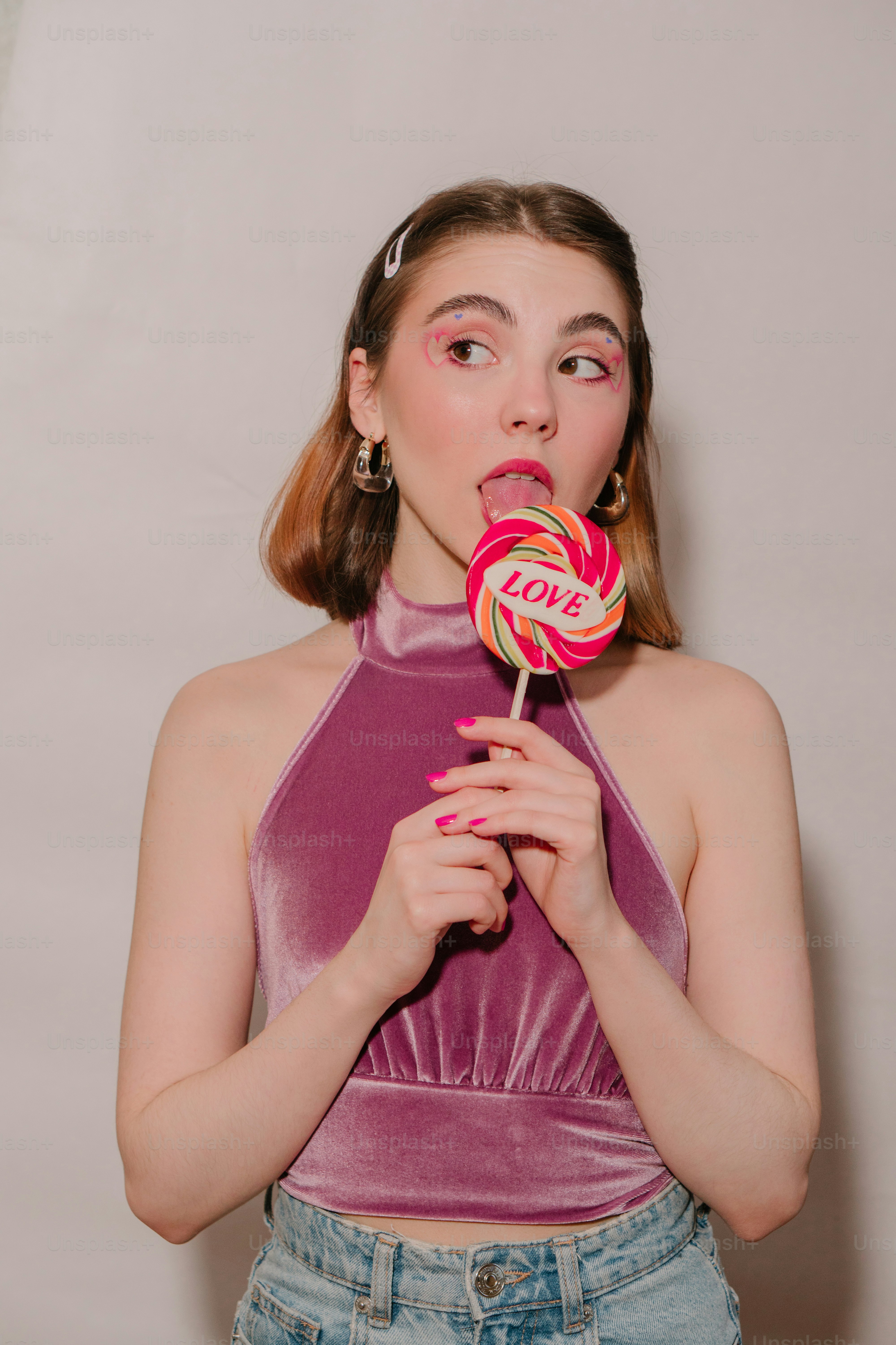 a girl in a purple top is holding a lollipop