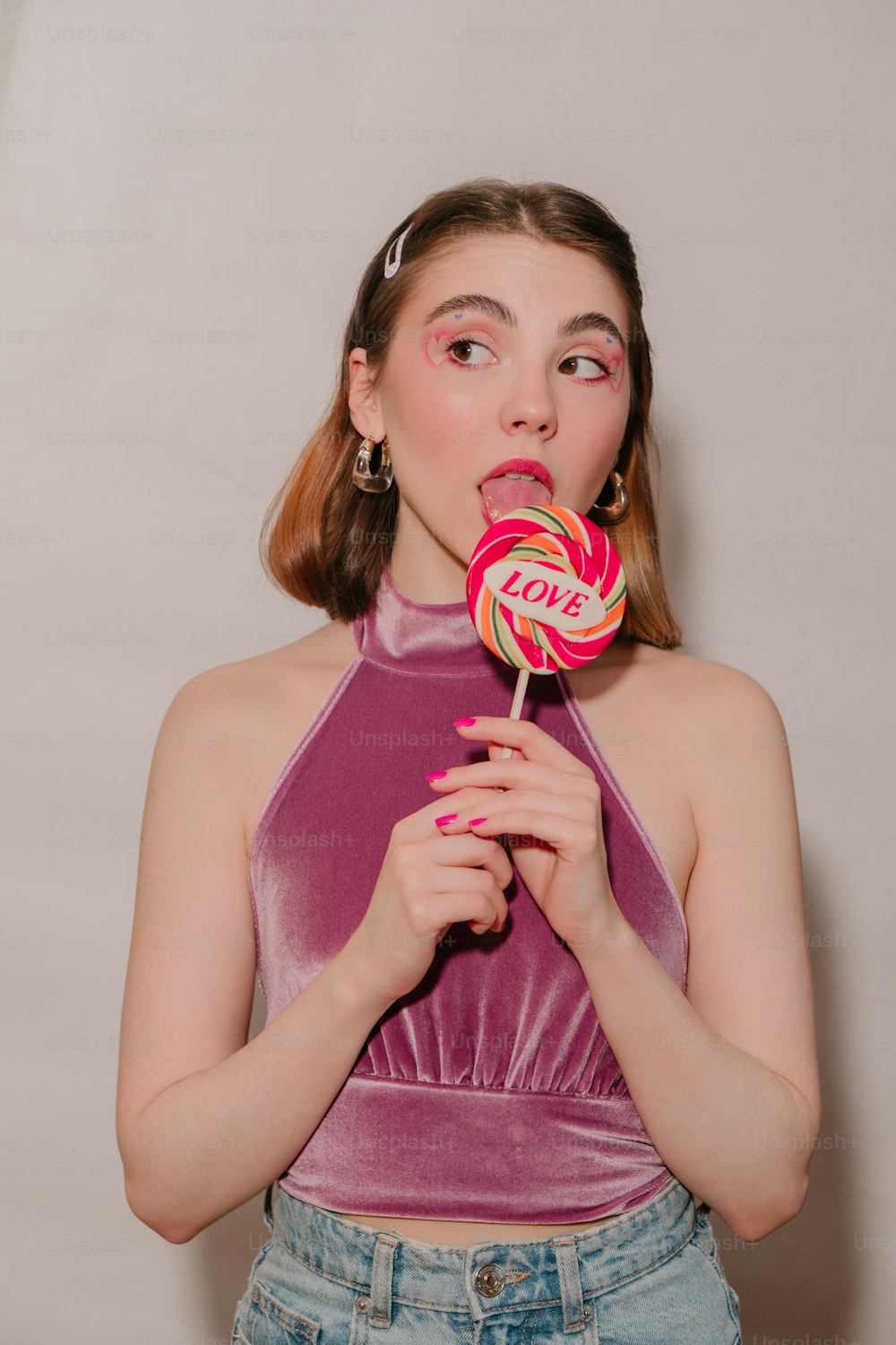 a girl in a purple top is holding a lollipop