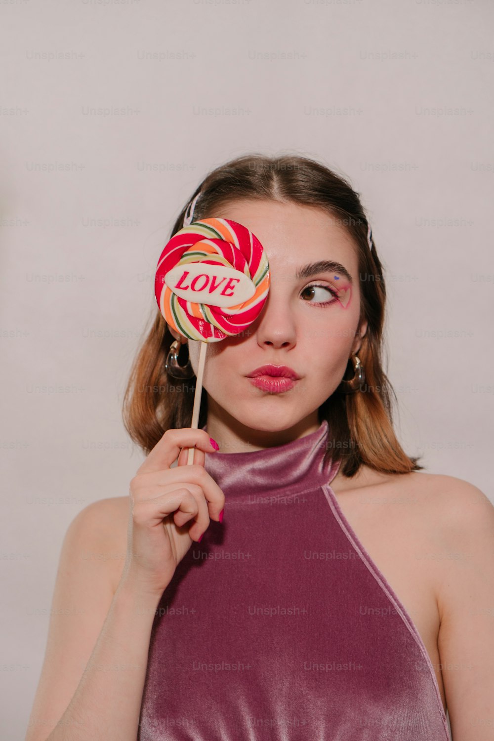 a woman holding a lollipop in front of her face