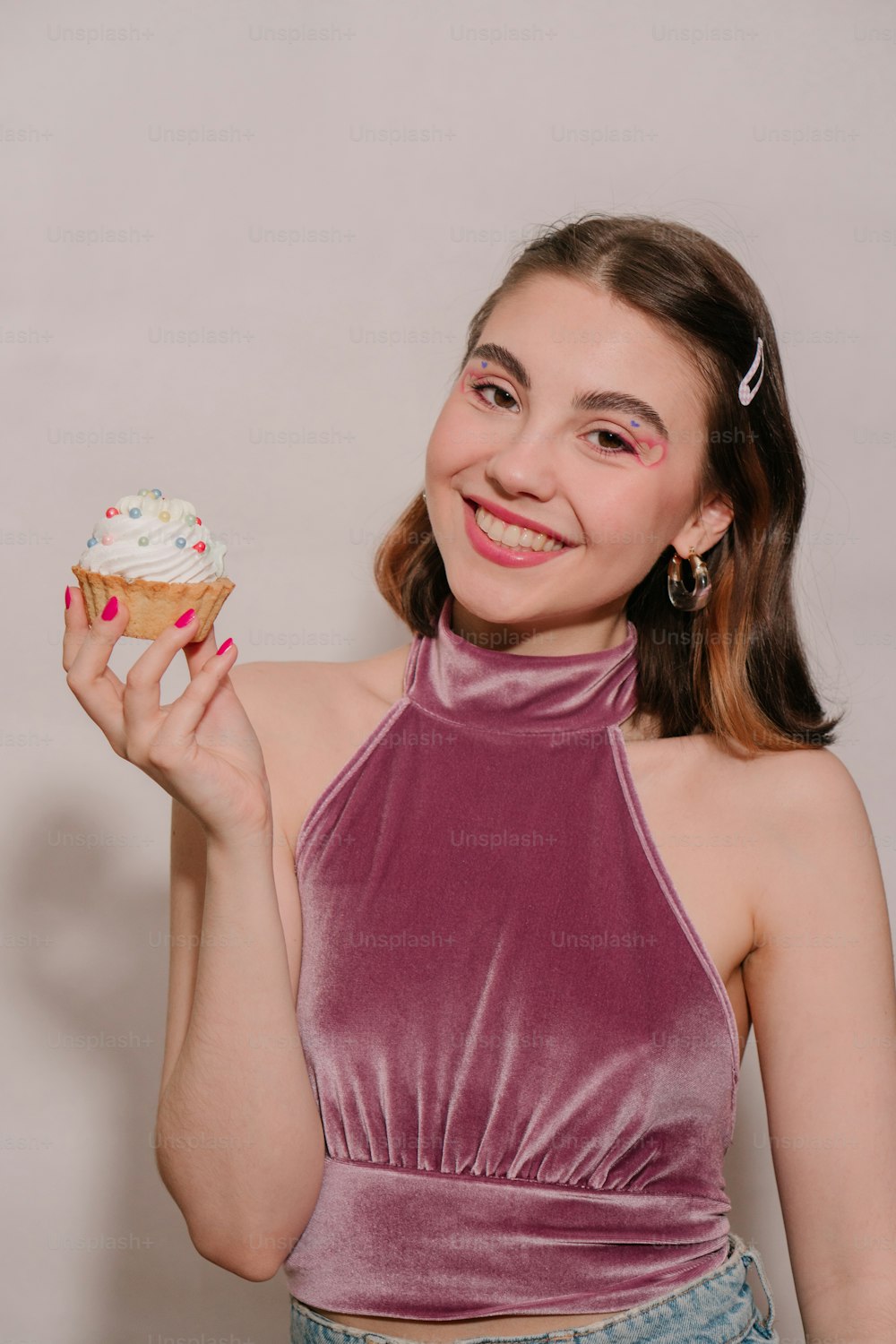 a woman holding a cupcake in her right hand