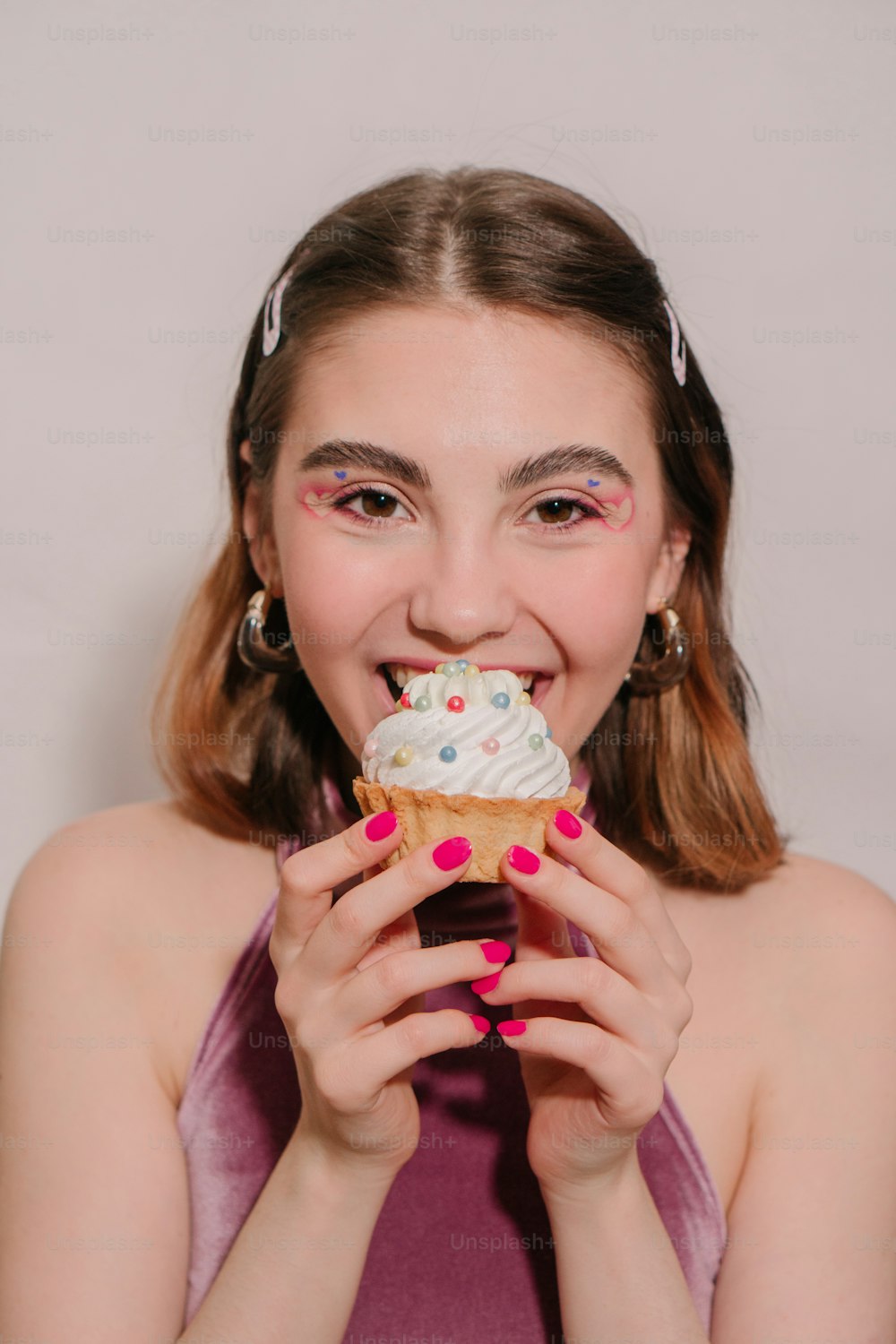 a young woman eating a frosted cupcake with sprinkles