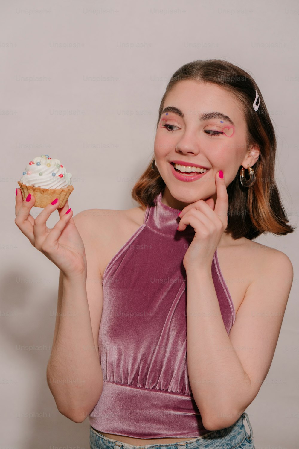 uma mulher segurando um cupcake em sua mão direita