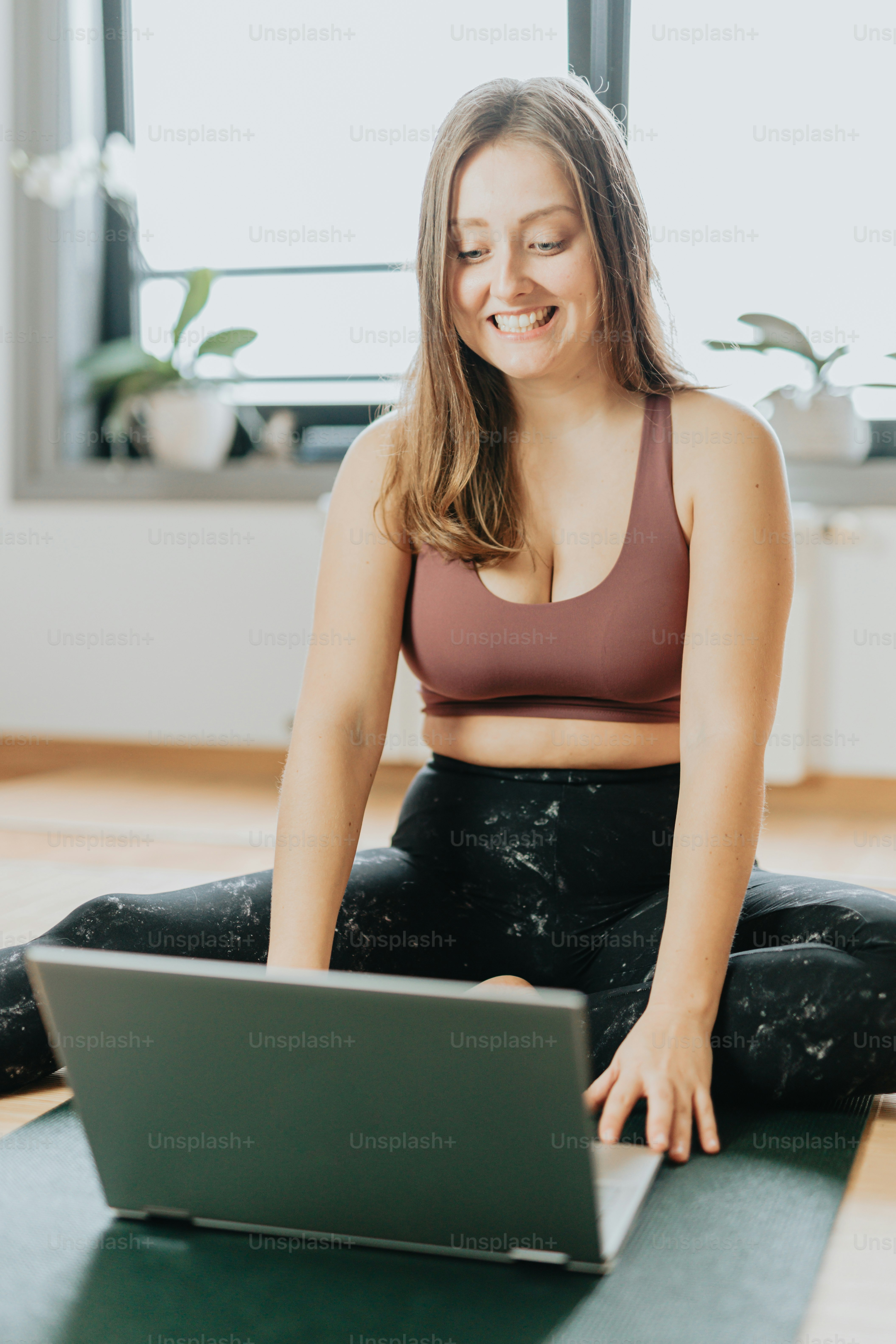 A woman sitting on a yoga mat using a laptop photo – Laptop Image on ...