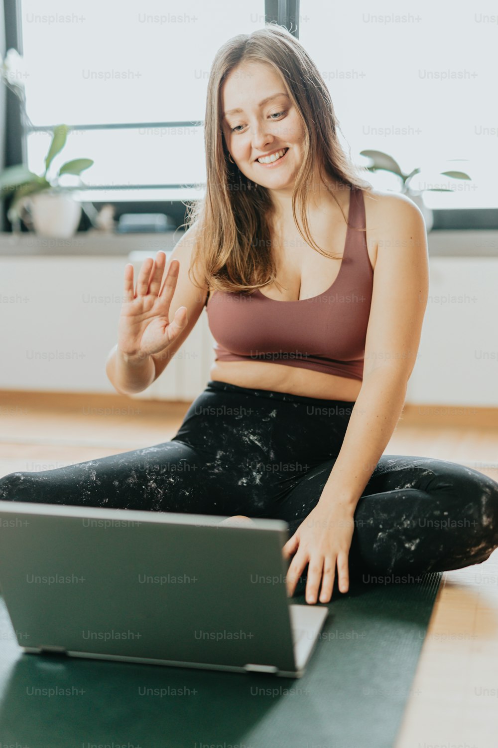Une femme assise sur un tapis de yoga utilisant un ordinateur portable