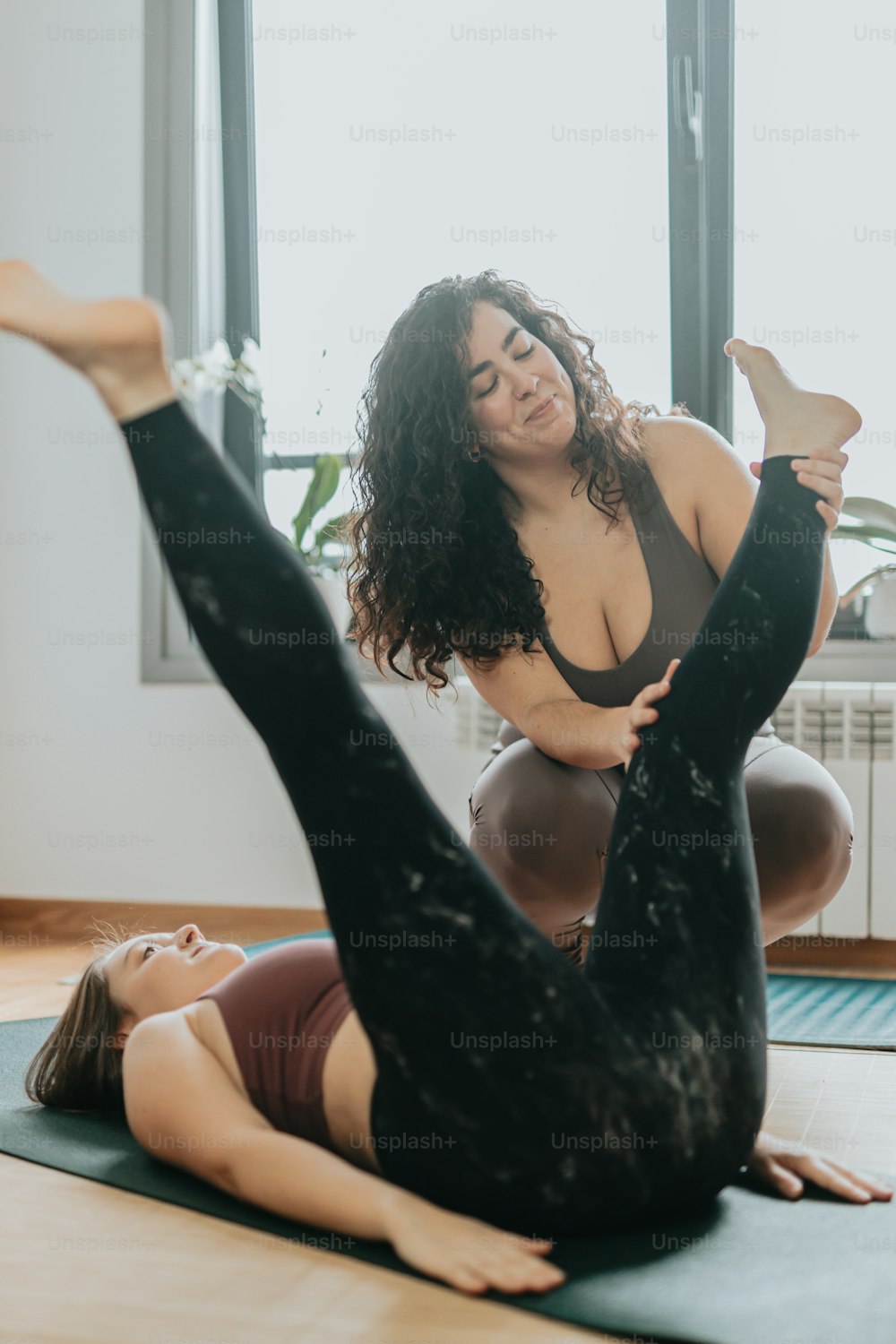 Due donne che fanno yoga su una stuoia davanti a una finestra