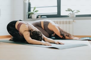 Dos mujeres están haciendo yoga en una habitación