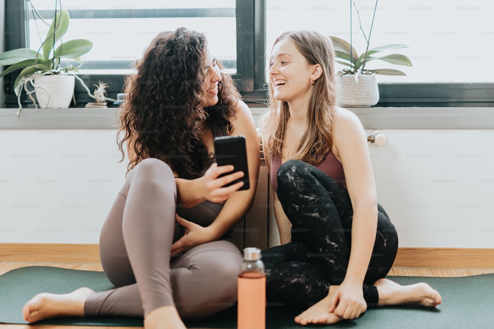 two women sitting on a yoga mat talking to each other
