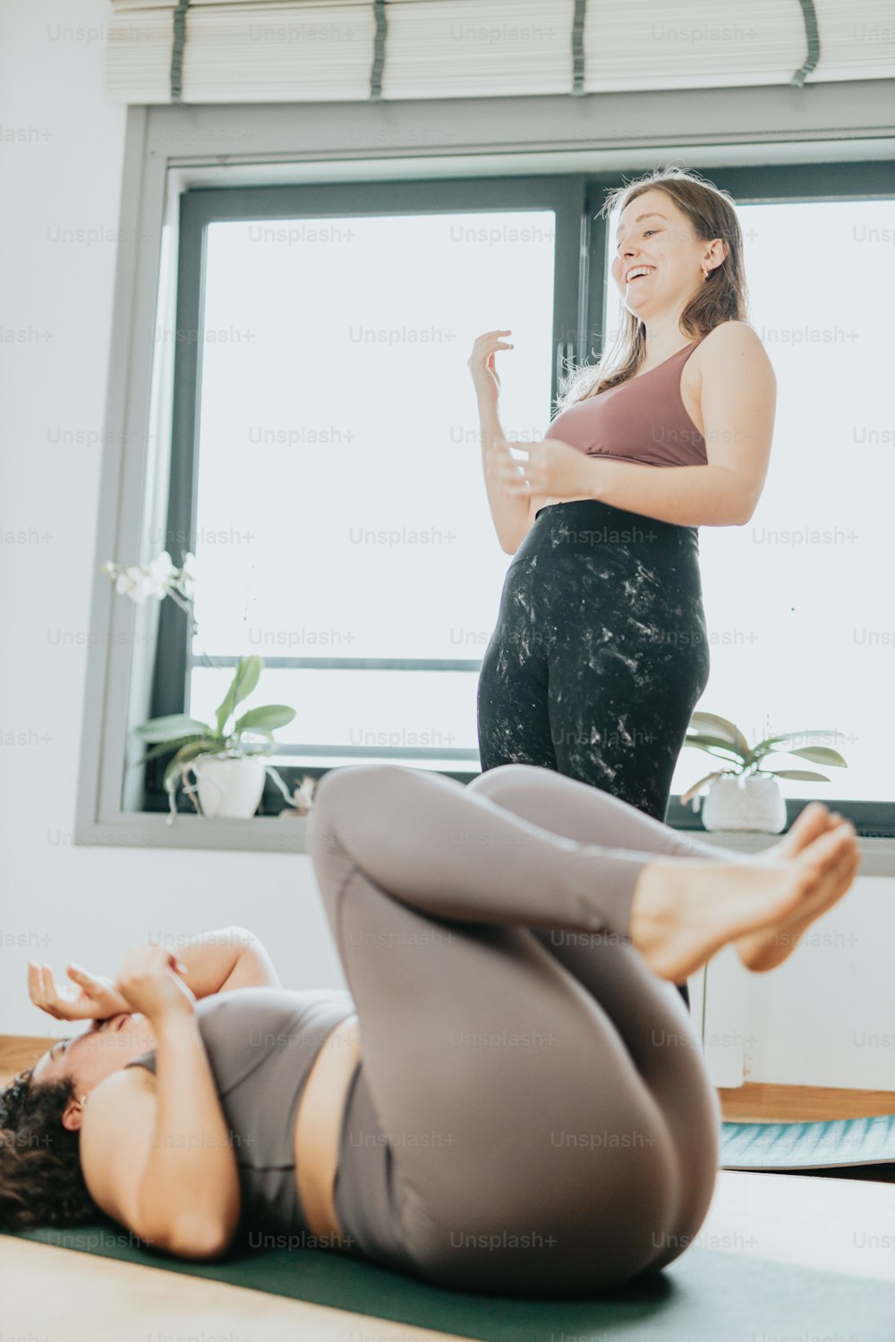 a woman in a yoga pose with another woman in the background