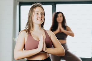 two women doing yoga in front of a window