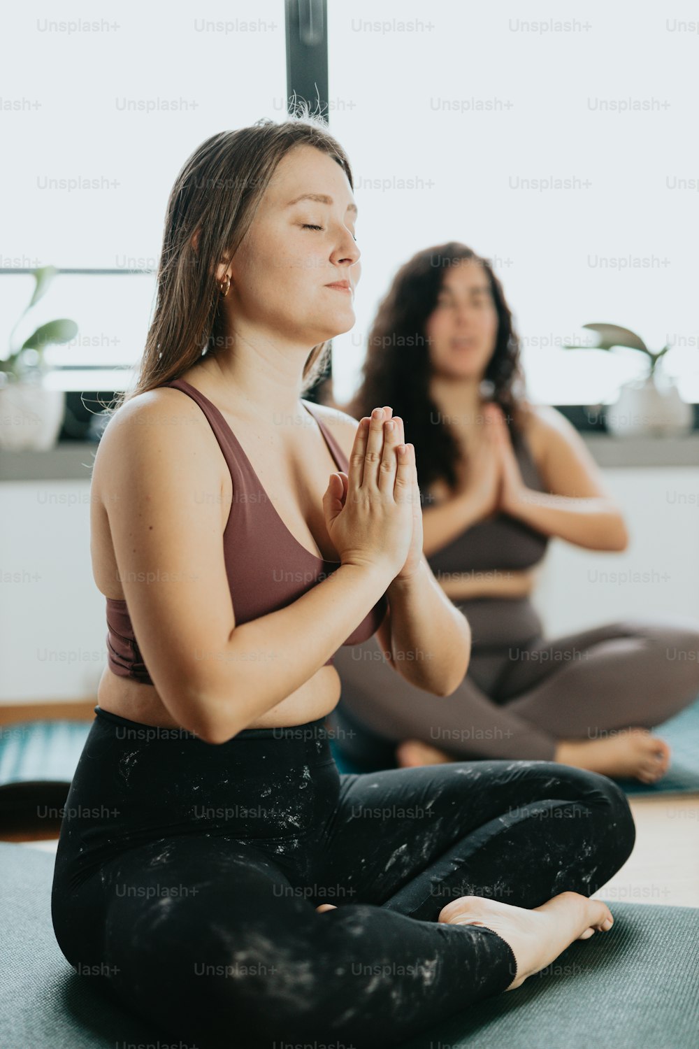 Dos mujeres sentadas en una pose de yoga con los ojos cerrados