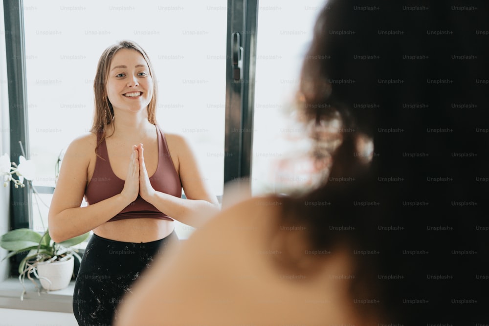 a woman standing in front of a mirror doing yoga