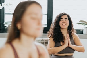 a woman sitting in a yoga position with her hands together