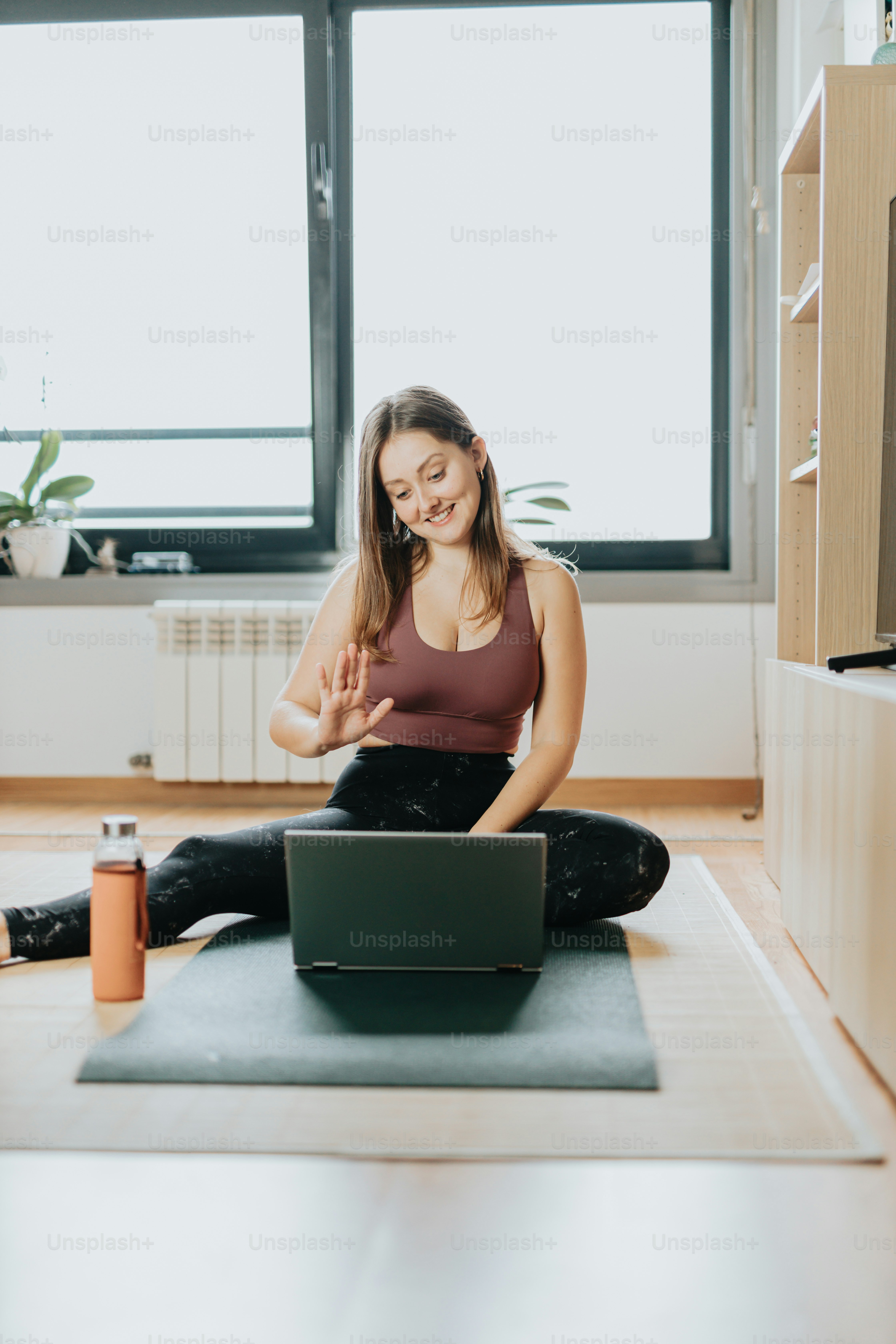 A woman sitting on a yoga mat using a laptop photo – Laptop Image on ...
