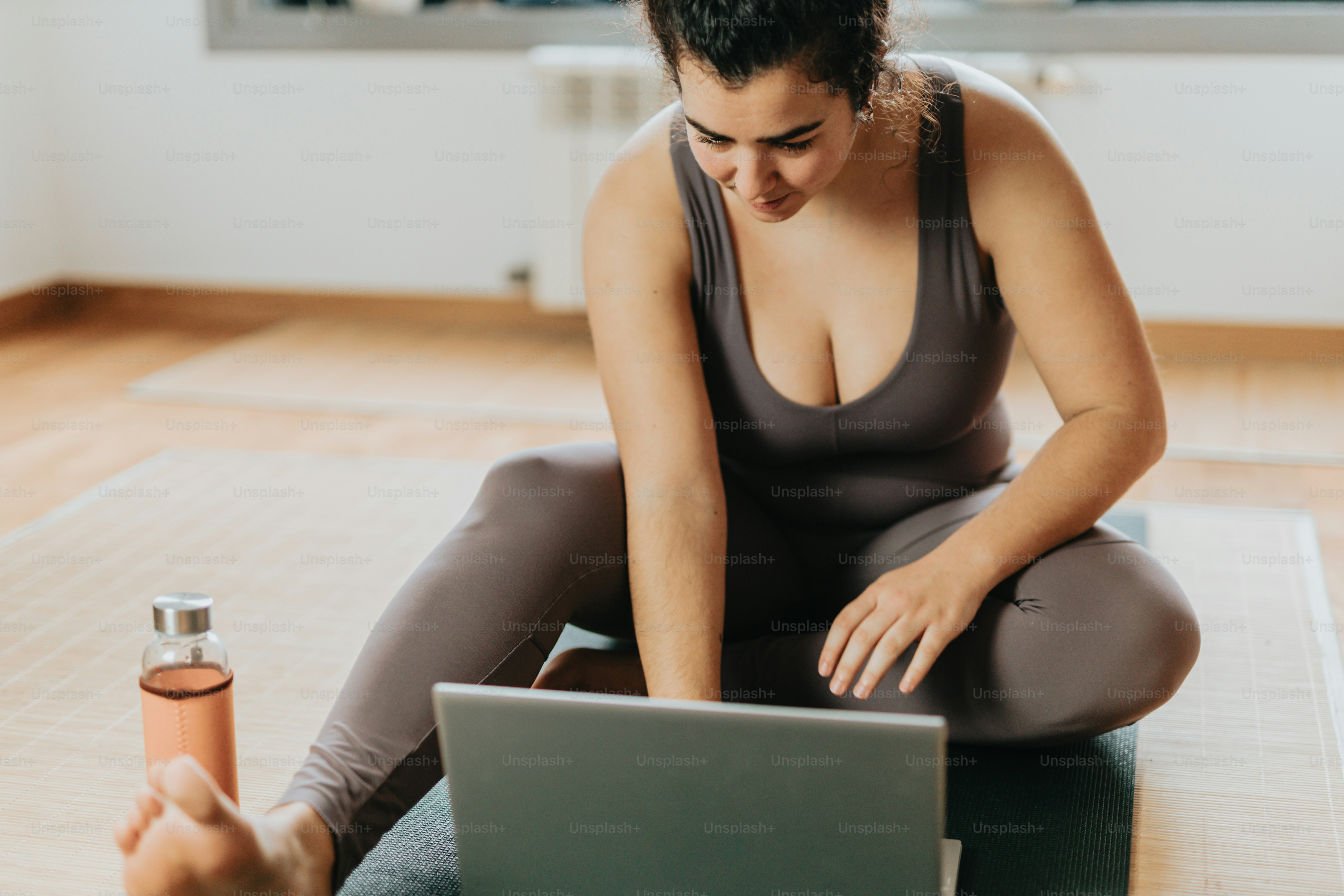 A woman sitting on a yoga mat using a laptop photo – Laptop Image on ...