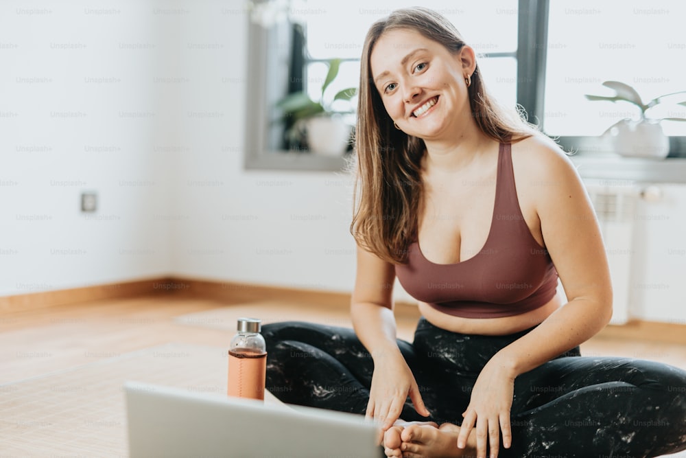 Une femme assise par terre avec un ordinateur portable