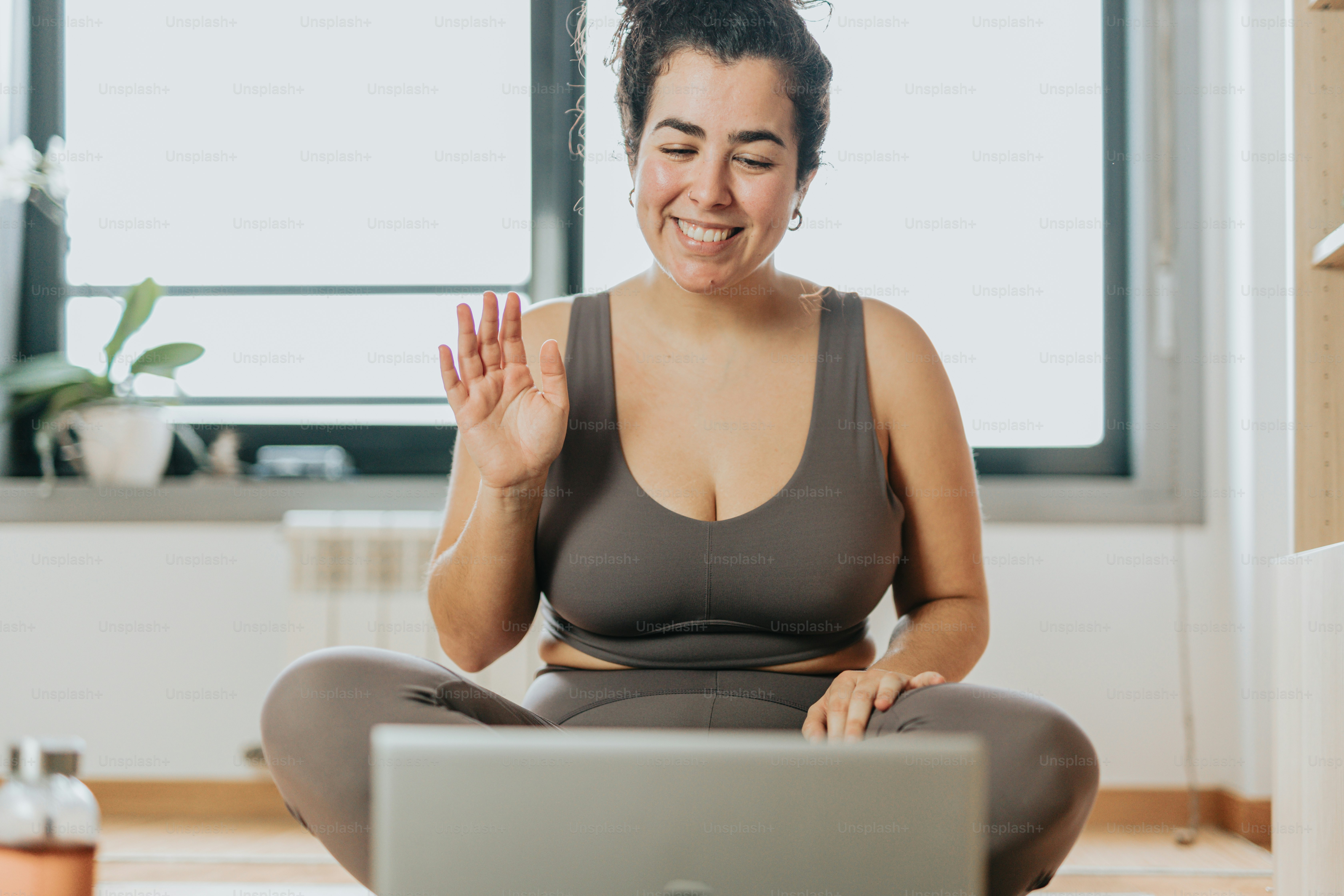 A woman sitting on a yoga mat with a laptop in front of her photo ...