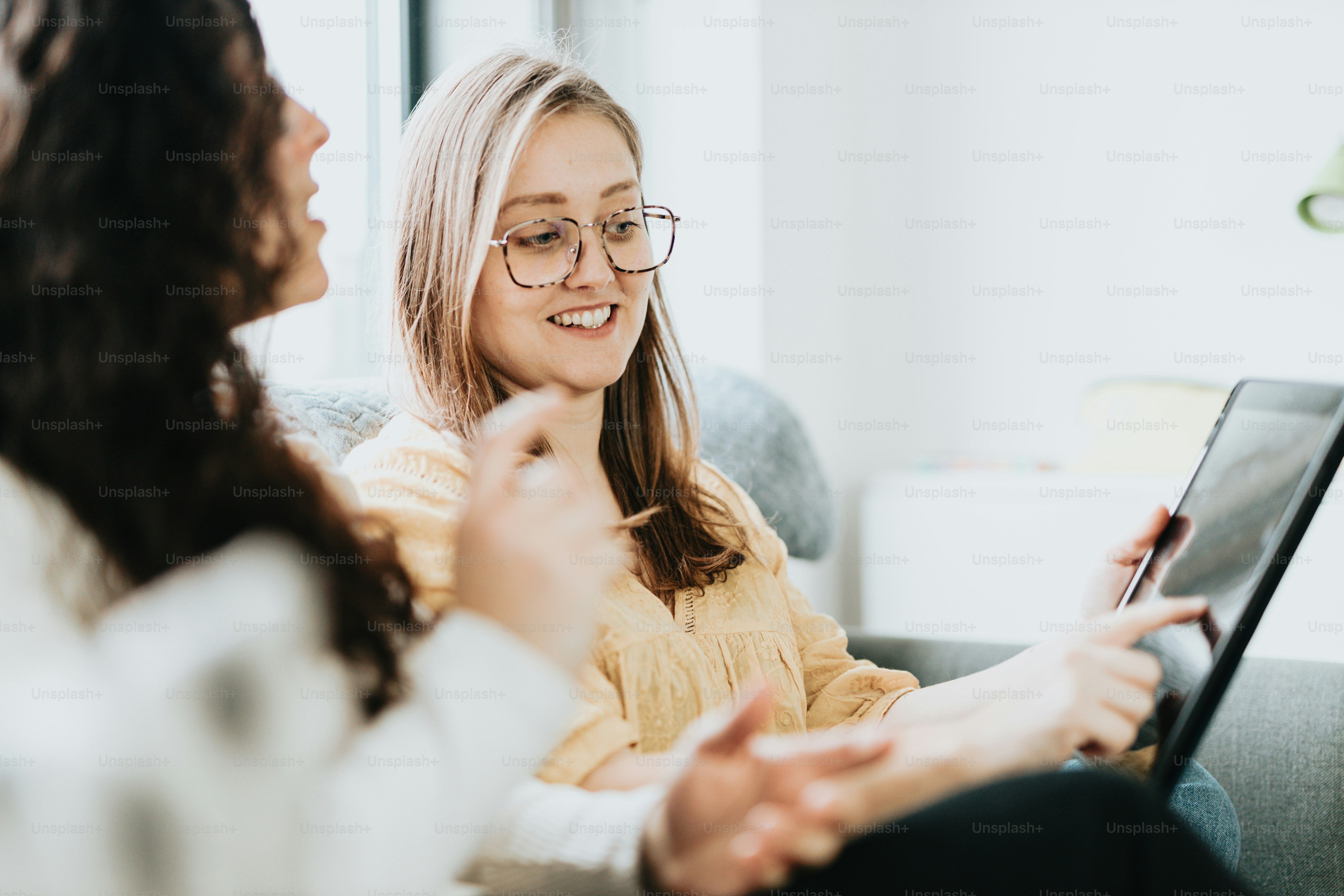 ソファに座ってタブレットを見ている2人の女性
