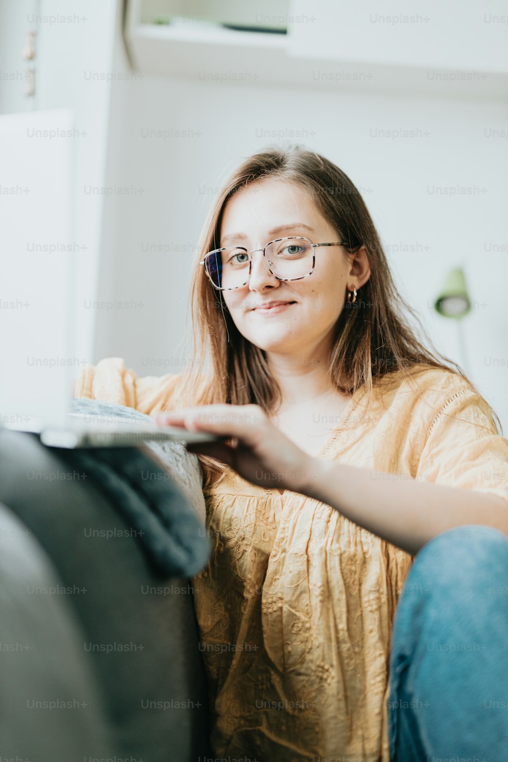 a woman sitting on a couch holding a laptop computer