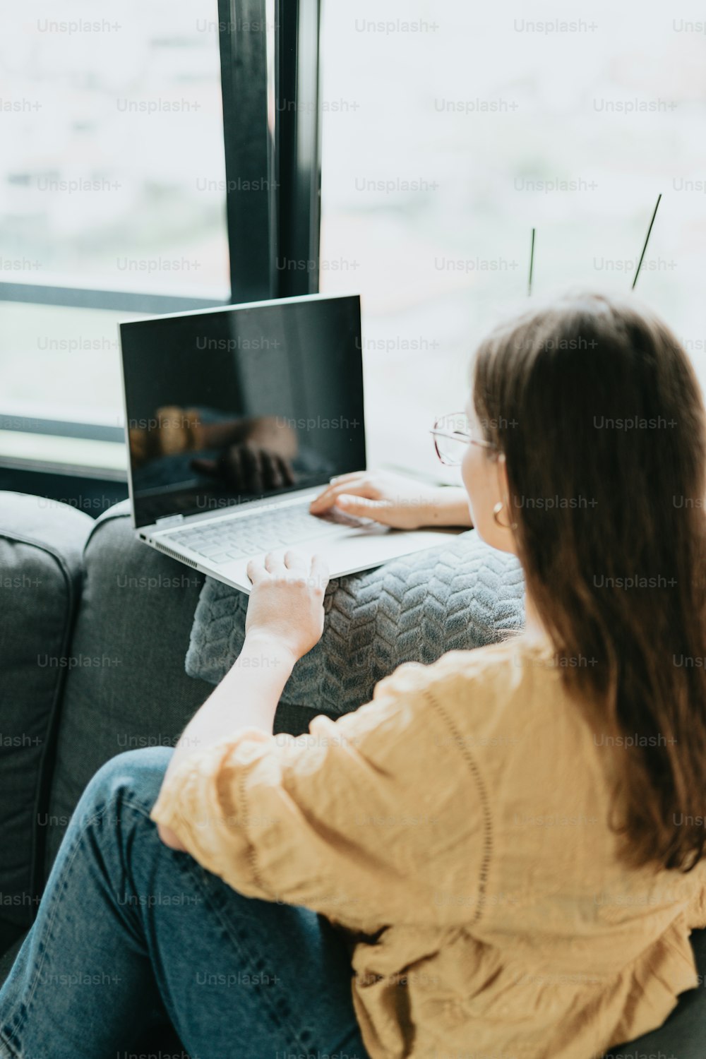 Una mujer sentada en un sofá usando una computadora portátil