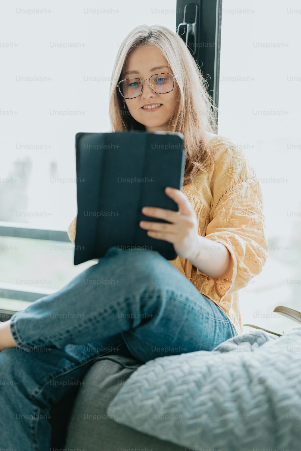 a woman sitting on a couch looking at a tablet