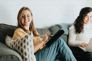 duas mulheres sentadas em um sofá com laptops