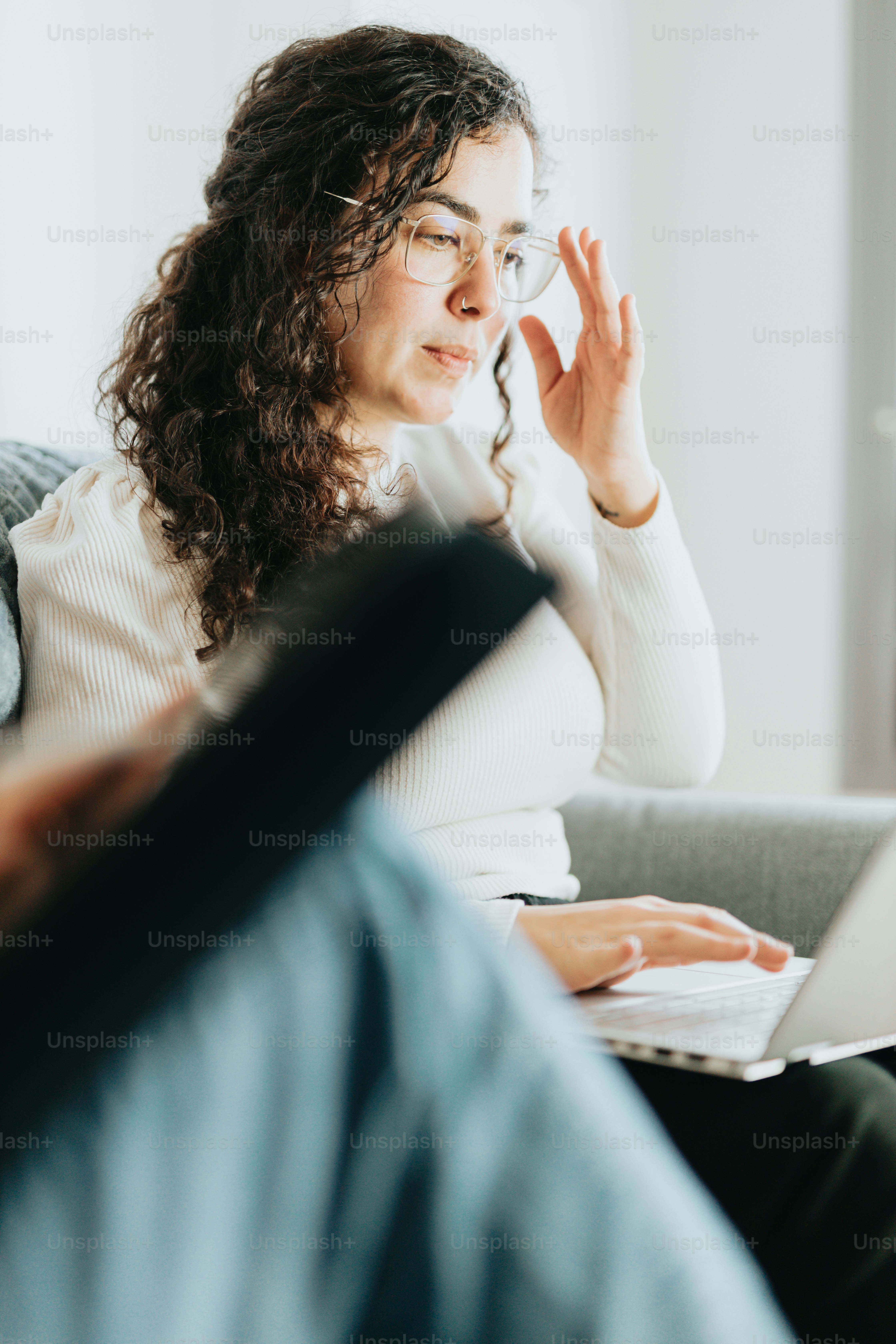 a woman sitting on a couch looking at a laptop