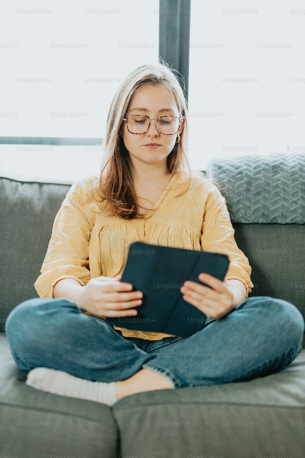 a woman sitting on a couch holding a tablet
