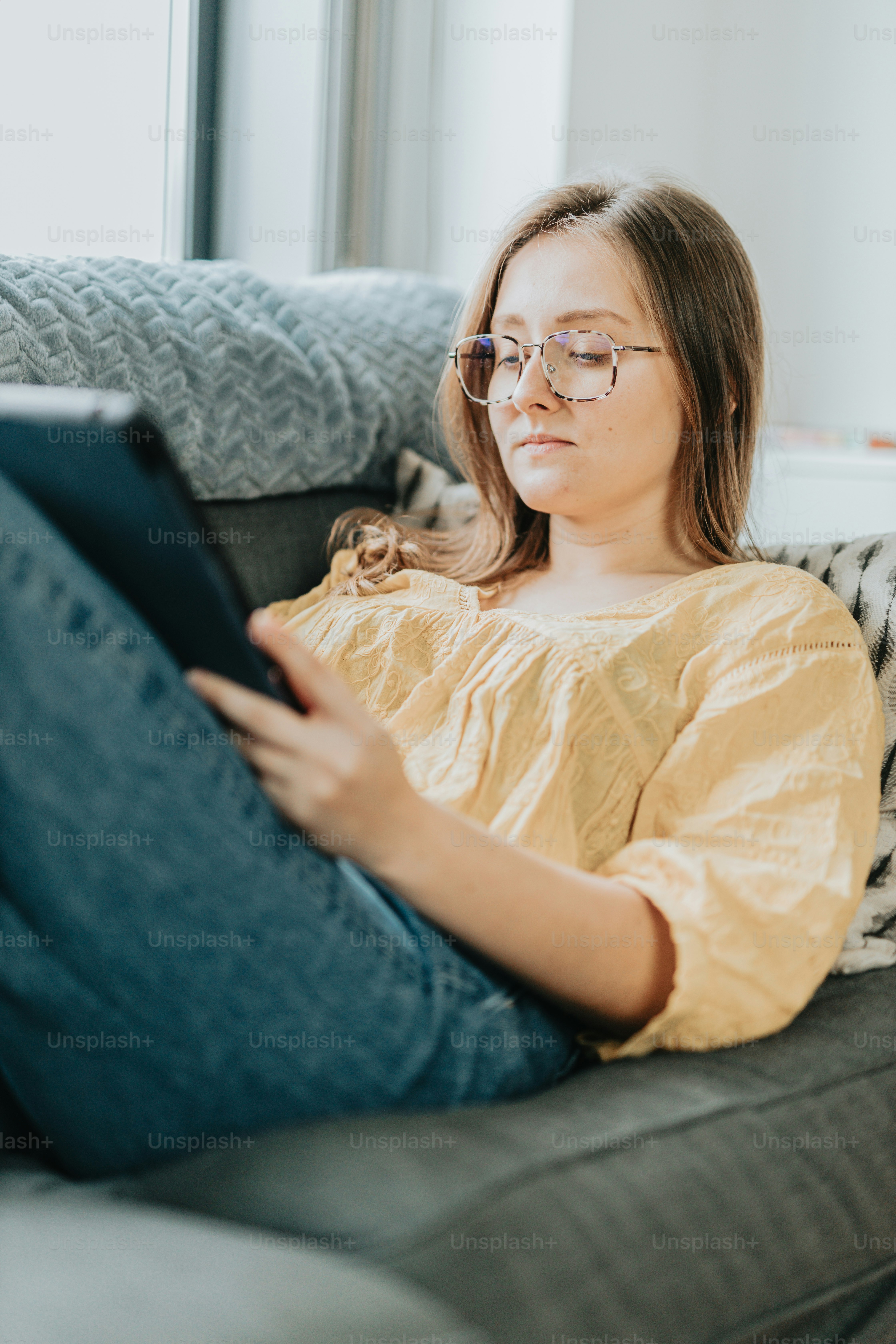 a woman sitting on a couch looking at a tablet