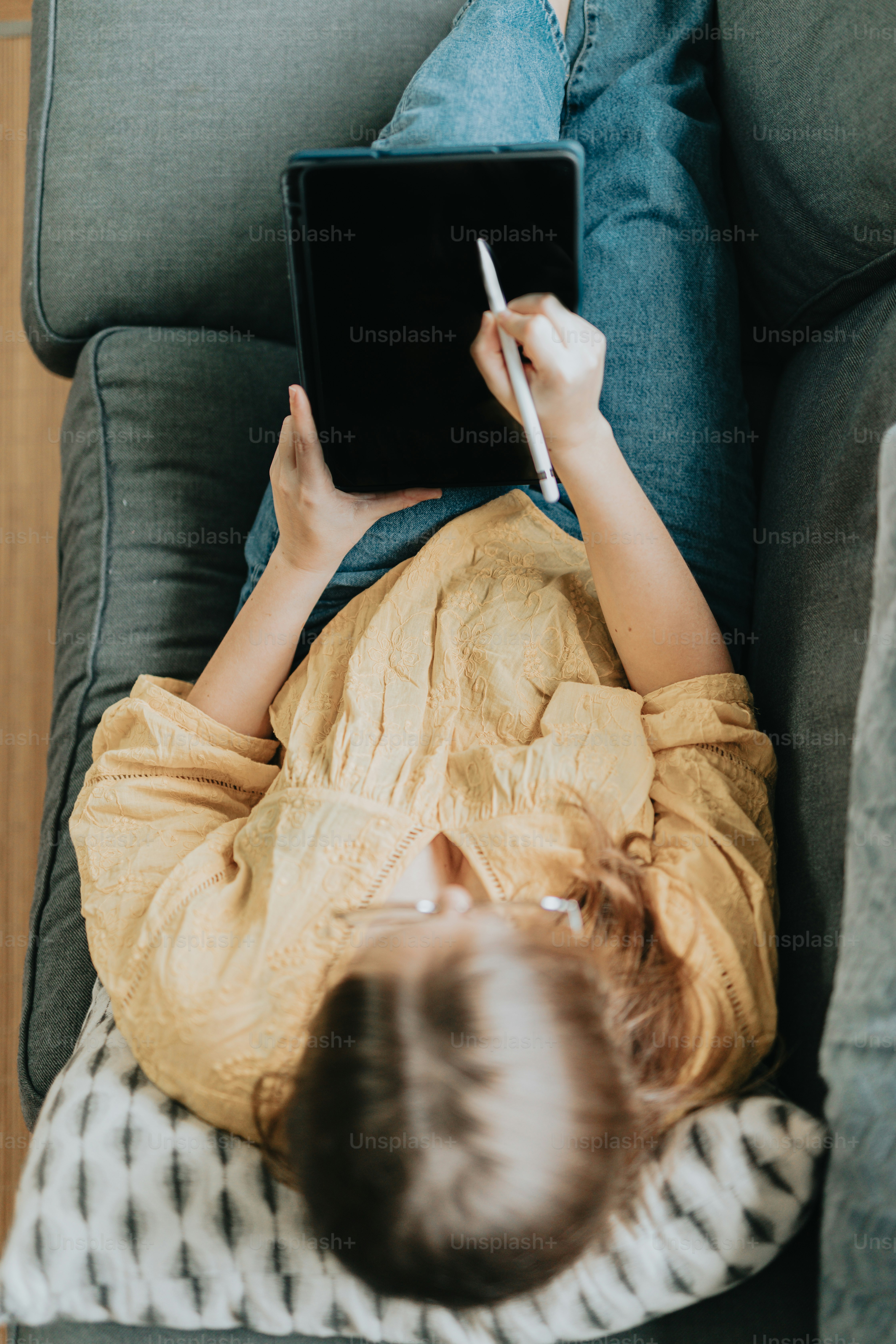 a young boy laying on a couch using a tablet