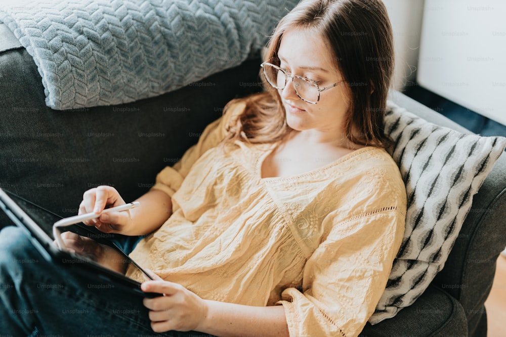 a woman sitting on a couch using a tablet